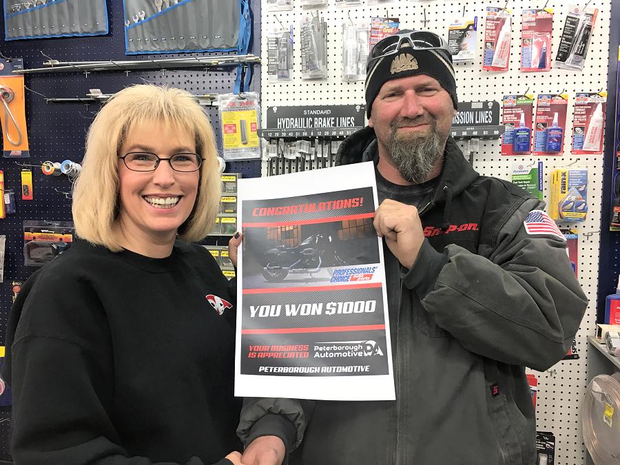 Pam Anderson from Lakefield Auto Parts store congratulates Darren Henry of ABC Customs, a customer of Peterborough Automotive,  on winning the $1,000 runner-up prize in this year's Professionals' Choice Auto Parts "Win a Harley Sportster" promotion.